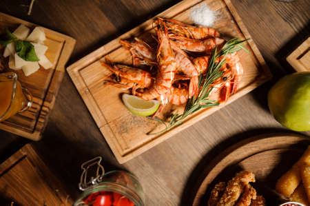Top view of tasty dish of large shrimps decorated with lemon and herbs on a wooden tableの写真素材