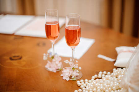 Two decorated glasses of champagne for bride and groom on the wooden table of the registry officeの写真素材