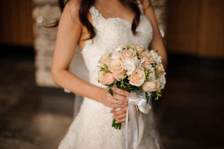 Bride in a lovely white dress holding a beautiful bouquet of wedding flowers made of tender roses in handの写真素材