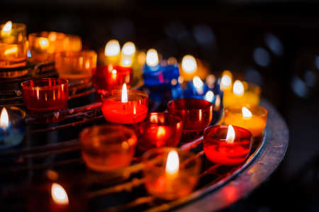 Burning candles in colorful candlesticks in a churchの写真素材