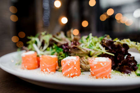 Delicious sushi with cheese, salmon and sesame served with green in the white plate. Food conceptの写真素材