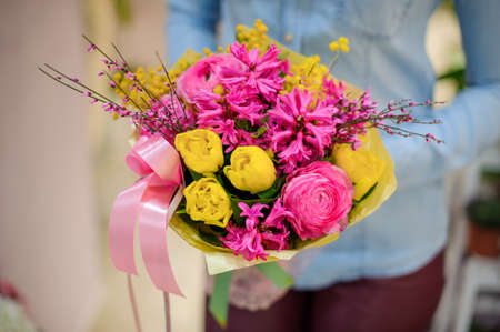 Florist holding a beautiful bright pink and yellow bouquet of flowers on the blurred background. Bouquet conceptの写真素材