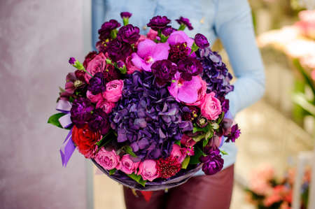 Florist holding a large and gorgeous purple bouquet of flowers on the blurred background. Bouquet conceptの写真素材