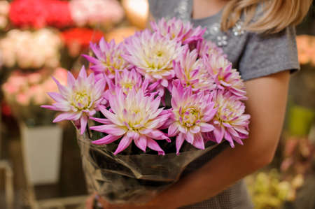 Young florist in a grey dress holding a beautiful bright pink flower composition. Bouquet conceptの写真素材