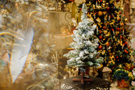 Little artificial Christmas tree decorated with artificial snow on the background of beautiful festive interiorの写真素材