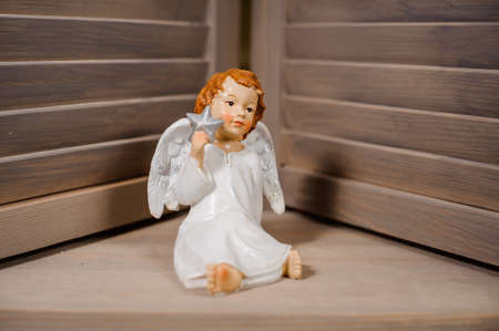 Decorative Christmas toy in a form of the cute redhead angel sitting on the floorの写真素材