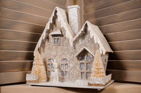 Decorative Christmas toy in a form of the house covered with snow on the wooden floorの写真素材