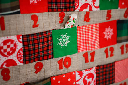 Soft textile Christmas calendar with pockets decorated with textile christmas patterns and trees hanging on the white wallの写真素材