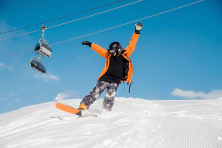 Young male snowboarder in colorful sportswear riding with snowboard from snow hill on the background...