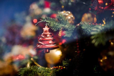 Glass Christmas tree decoration toy in the form of a red fir tree with a star on the background on lightsの写真素材
