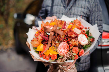 Man holding a beautiful colorful autumn bouquet of flowersの写真素材