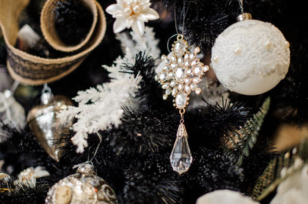Elegant Christmas tree decoration toys in white tones hanging on the fir tree covered with snow