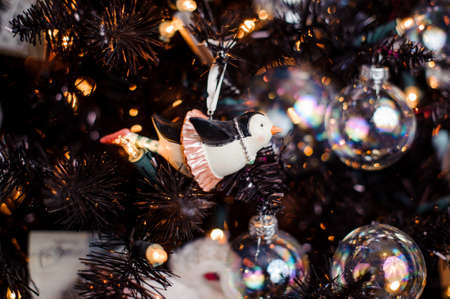 Cute Christmas tree decoration toy in the form of a penguin in skirt among glass balls and garlandsの写真素材