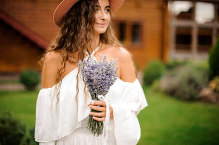 Beautiful woman dressed in white dress with bouquet of lavenderの写真素材