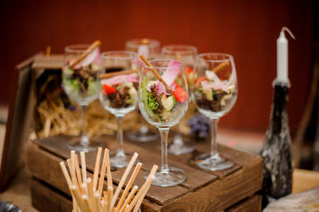 Fresh vegetable salad in elegant glasses on the wooden box among decor on the tableの写真素材