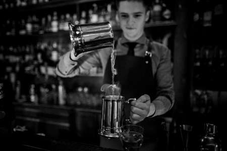 Black and white photo of young bartender making cocktail on the background of bar counterの写真素材