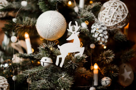 Beautiful Christmas tree branches decorated with snow, garlands and cute toys in white tones hanging on itの写真素材