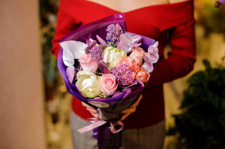 Beautiful bouquet of flowers in tender purple tones in woman s hands on the blurred indoors backgroundの写真素材