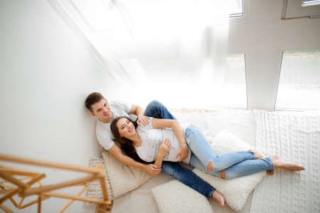 Top view of smiling pregnant woman with husband lying on the large white bed. Pregnancy conceptの写真素材