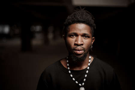african american guy in black clothes and white necklace and earring wearing dreadlocks and beardの写真素材