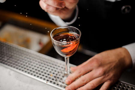 Mans hand holding a glass filled with the alcoholic drink with a slice of fresh orangeの写真素材