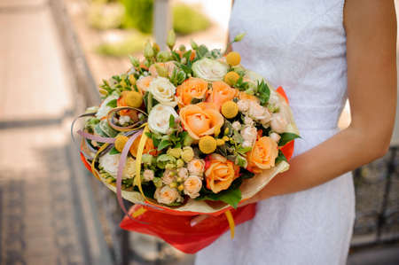 romantic woman in white dress holds a bouquet of kraspedia, roses, pion-shaped roses and succulentsの写真素材