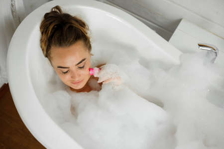 Top view portrait of young and beautiful woman lying in the bath with foam with her eyes closedの写真素材