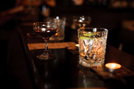 Cocktail glasses filled with alcoholic drinks on the bar counter against the background of dark bar hallの写真素材
