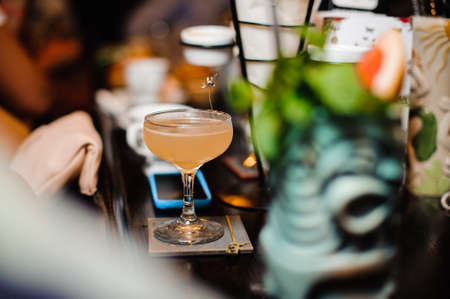 Elegant cocktail glass filled with alcoholic drink on the bar counter against the blurred background of barの写真素材