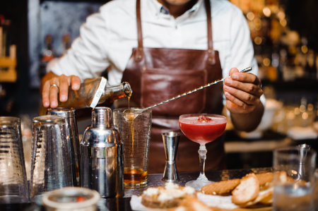 Bartender in a brown leather apron making fruit alcoholic cocktail standing behind the bar counterの写真素材