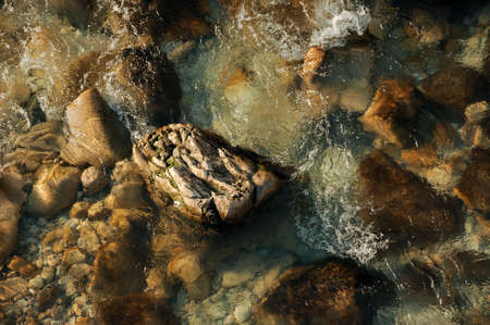 Top view of wide stones on the bottom of clear and cold flowing forest riverの写真素材
