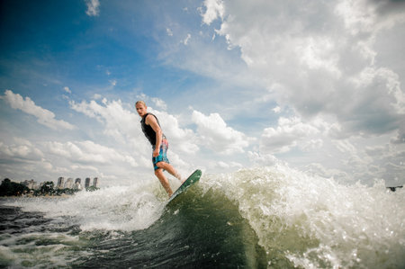 athletic surfer rides the waves by wakeboard on the background of the beautiful clouds on the river