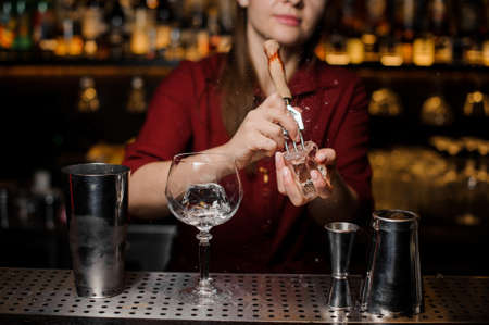 Professional bartender girl breakin a piece of ice for a fresh cocktail at the steel bar counterの写真素材