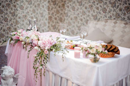 Decorated in white and pink tones wedding buffet table with tasty dishes and champagne on the indoors backgroundの写真素材