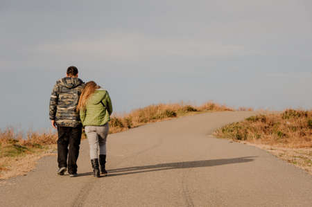 Outdoor shot of young couple in love walking on pathway on the beautiful landscape on the backgroundの写真素材