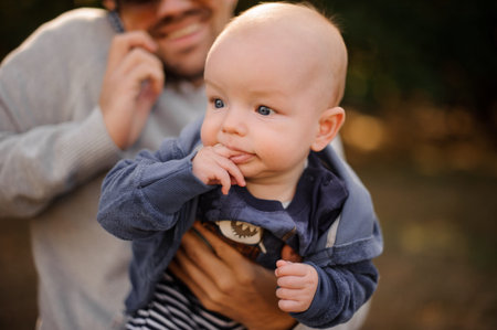 Smiling bearded father spending time with a little blue-eyed son putting fingers into his mouth
