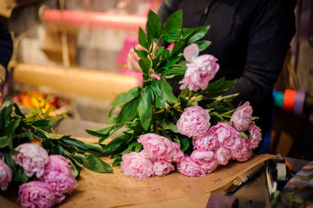 Professional florist making a bouquet of fresh and tender pink peonies in a flower shopの写真素材