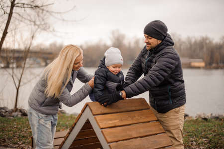 Smiling parents walking with a little son in the park near the pond on the cloudy dayの写真素材