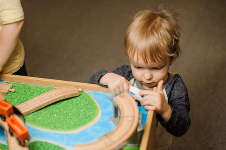 Cute little boy is playing with toy wooden train in the playing room in concentrationの写真素材