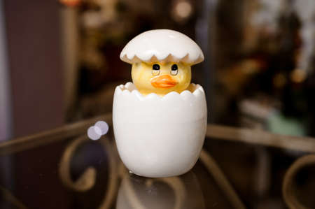 Symbol of Easter toy cute little yellow chicken coming out of the white egg isolatedの写真素材