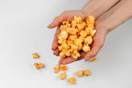 Woman hands holding fresh and warm salty popcorn with a cheese taste on the white backgroundの写真素材