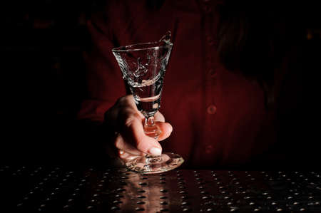 Woman hand holding a cocktail glass filled with a fresh alcoholic drink on the bar counterの写真素材