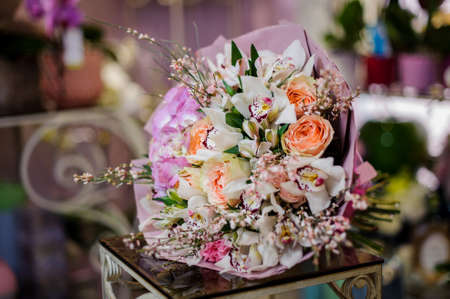 Wonderful bouquet of amazingly beautiful white orchids, peach roses and violet hydrangea wrapped into a violet paperの写真素材