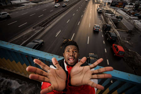 Top view of afro-amercan man rising his hands up and screaming on the background of the city roadの写真素材