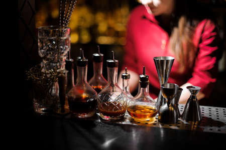 Barman essentials, such as alcohol bottles measuring piles on the blurred background of female barthenderの写真素材