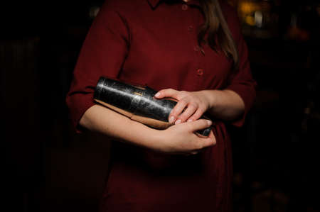 Bartender girl holding in hands a steel shaker with a fresh cocktail dressed in the red shirtの写真素材