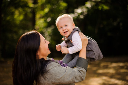 Happy brunette mother playing and having fun with a laughing daughter in the beautiful autumn park