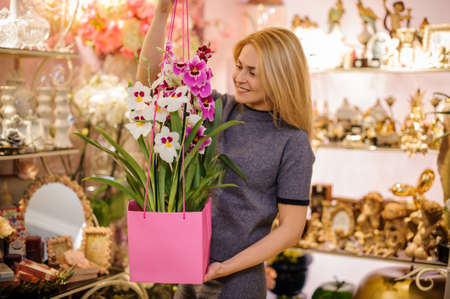 Girl holding in her hands a beautiful bouquet of rose and white colour flowers decorating with a green leaves in pink boxの写真素材