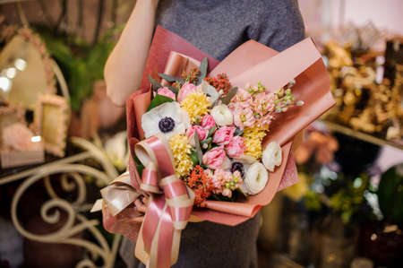Girl holding in her hands a beautiful bouquet of rose colour tulips, yellow hyacinth, white ranunculuse and another flowersの写真素材