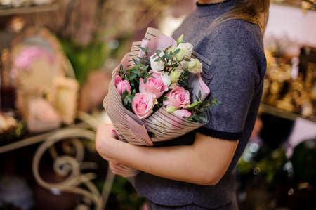 Girl holding a beautiful bouquet of pink and white roses decorating with a green leavesの写真素材